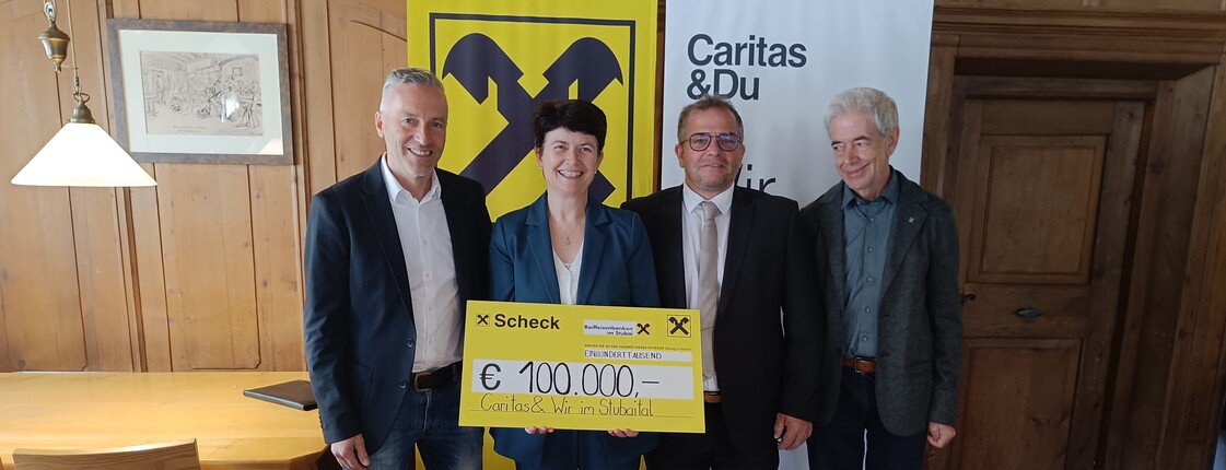 Vier Personen stehen vor einem Roll-Up der Raiffeisenbank und einem der Caritas.