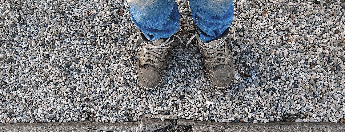 Ein Paar abgetragene Sneaker auf Asphalt.