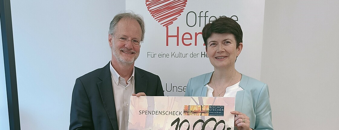 Zwei Personen halten gemeinsam einen Spendenscheck über 10.000 Euro in den Händen.