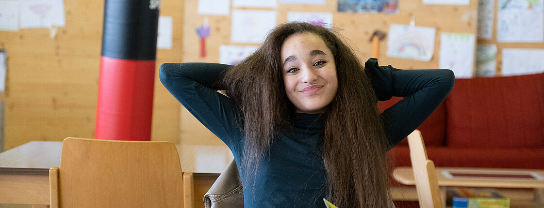 Portrait einer Schülerin mit verschränkten Armen hinter dem Kopf.