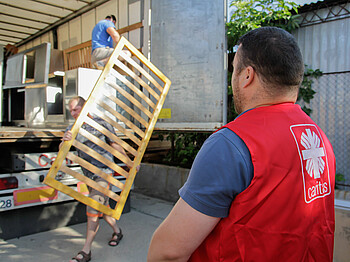 Caritas Mitarbeiter laden Möbel in einen Lastkraftwagen.