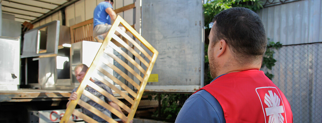 Caritas Mitarbeiter laden Möbel in einen Lastkraftwagen.