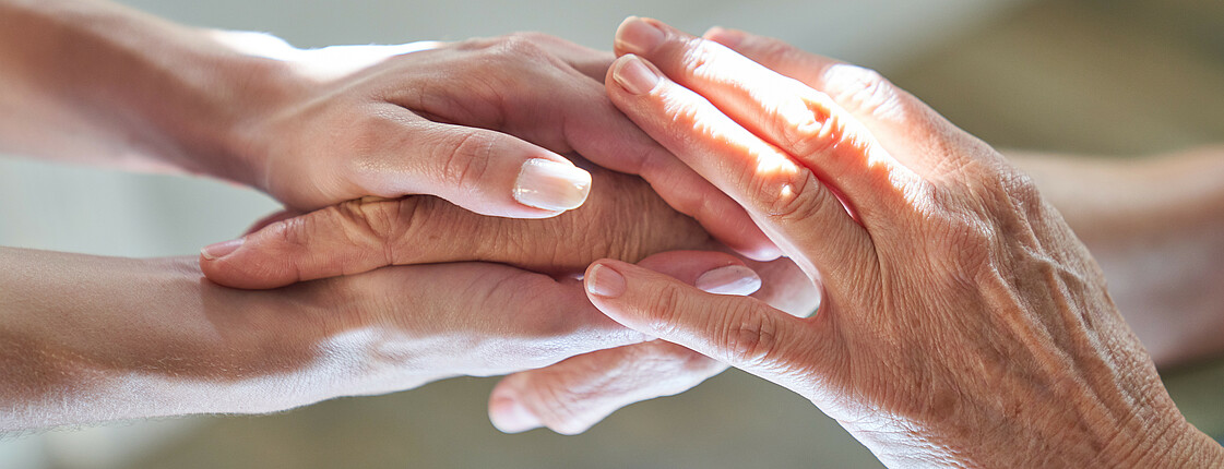Junge Hände halten alte Hände als Symbol für Beistand und Anteilnahme.