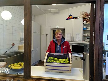 Dienststellenleiterin mit einer Kiste voll Äpfel