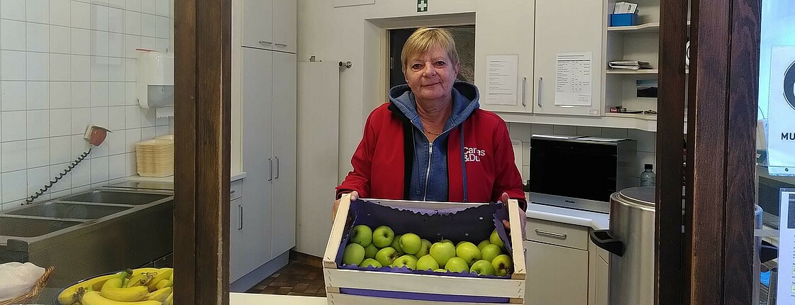 Dienststellenleiterin mit einer Kiste voll Äpfel