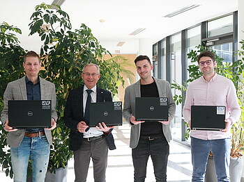 Gruppenfoto von vier Männern mit Laptops in den Händen.
