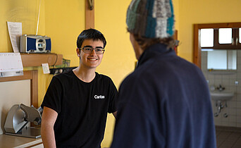 In einer Wärmestube ist ein Caritas-Mitarbeiter im Gespräch mit einem Klienten.